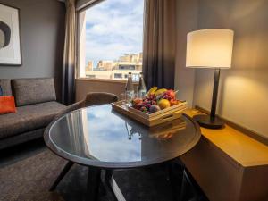 a living room with a glass table with a bowl of fruit at Novotel Sydney Darling Harbour in Sydney