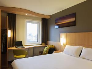a hotel room with a bed and a desk and a window at ibis Rotterdam Vlaardingen in Vlaardingen +78 photos