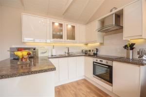 eine Küche mit weißen Schränken und Granitarbeitsflächen in der Unterkunft The Barn in Little Maplestead