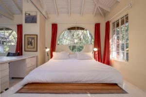 a bedroom with a large bed with red curtains at Pool House Studio by YourHost Karen Nairobi in Nairobi