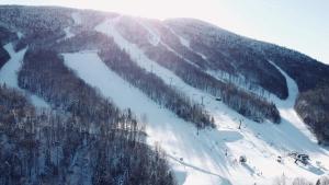 een met sneeuw bedekte berg met bomen en een skipiste bij Sauna & Pool Table - Nordik Attitude in Saint-Philémon