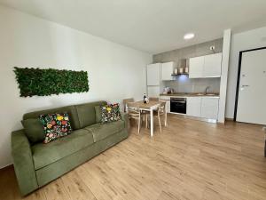 Una sala de estar con un sofá verde y una cocina. en Suite dei Principi 2, aeroporto e parcheggio gratuito, en Bari