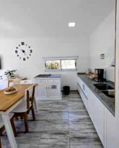 een keuken met een tafel en een klok aan de muur bij Casa con jardín Las Marías 1 in Miramar