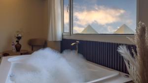 a bath tub filled with water with a window at pyramids palace view With Rooftop Access in Cairo +66 photos