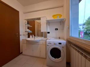 une salle de bains avec lave-linge et lavabo dans l'établissement Casa Vacanza Ninfea, à Paratico