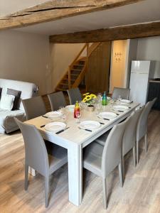 a dining room table with chairs and a large white table at Les Glaneuses Gîte Le Grand 8 centre-bourg 3 min du Puy duFou in Les Épesses