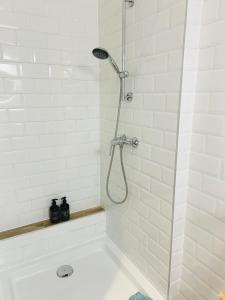 a shower in a white tiled bathroom with a tub at Garden Apartment in Kecskemét +7 photos