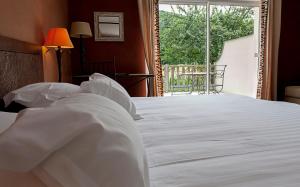 1 dormitorio con 1 cama blanca grande y ventana en Hôtel La Gentilhommière, en Nuits-Saint-Georges