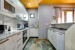 a large kitchen with white cabinets and a window at Aleqs in Tbilisi City +13 photos