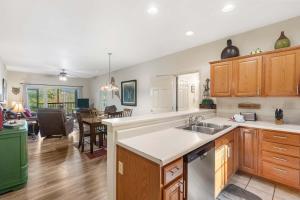 a kitchen with wooden cabinets and a living room at Fairway To Heaven - For 8ppl in Branson West