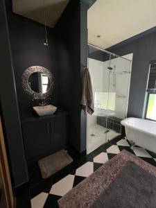 a black bathroom with a sink and a mirror at Franschhoek Guest Suite in Franschhoek
