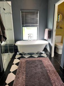 a bathroom with a tub and a toilet and a rug at Franschhoek Guest Suite in Franschhoek