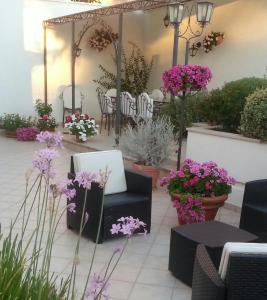 un patio con flores púrpuras, mesas y sillas en Il Giardino Delle Sete, en Mesagne