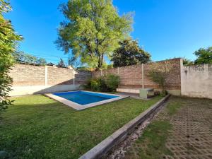 a swimming pool in a yard next to a brick wall at Colina Garden departamento in Victoria