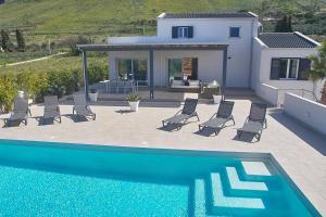 a swimming pool with chairs and a house at Villa Biancolilla in Castellammare del Golfo