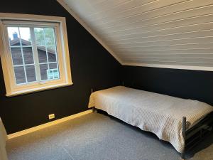 ein kleines Schlafzimmer mit einem Bett und einem Fenster in der Unterkunft Feriehus med stort lekerom in Kristiansand