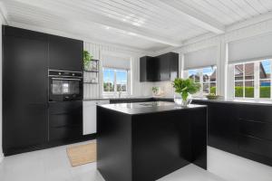 eine Küche mit schwarzen Schränken und einer schwarzen Insel in der Unterkunft Feriehus med stort lekerom in Kristiansand