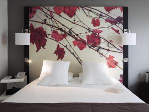 a bedroom with a white bed with red flowers on the wall at Mercure Bordeaux Centre Ville in Bordeaux