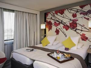 a hotel room with a bed with a tree mural on the wall at Mercure Bordeaux Centre Ville in Bordeaux