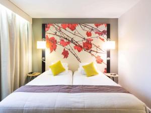 a bedroom with two beds with yellow and red leaves on the wall at Mercure Bordeaux Centre Ville in Bordeaux
