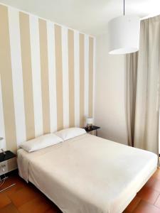 un lit blanc dans une chambre avec un mur rayé dans l'établissement Sori e Mare Loft, à Sori