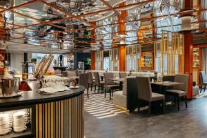 a restaurant with tables and chairs and a bar at MONDI Hotel Bellevue Gastein in Bad Gastein