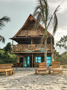 a wooden house with chairs and a palm tree at Cabaña Kokkos Del Mar in Santa Marta