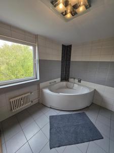 une grande baignoire blanche dans une salle de bain avec une fenêtre dans l'établissement Cozy city apartment Neuwied, à Neuwied