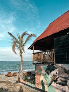 a building on the beach with a palm tree at Cabaña Kokkos Del Mar in Santa Marta