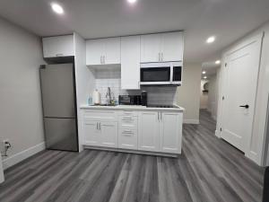 a kitchen with white cabinets and a refrigerator at Cozy Haven Suite in Moncton