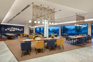 a dining room with tables and chairs and windows at voco Ningbo Dongqian Lake by IHG in Ningbo