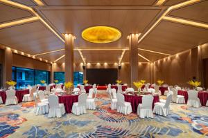 a ballroom with tables and white chairs and a stage at voco Ningbo Dongqian Lake by IHG in Ningbo +23 photos