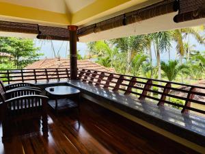 KappilにあるMaadathil Cottages & Beach Resortのヤシの木が植わるバルコニー(テーブル、椅子付)