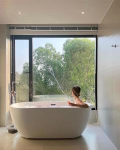 Una mujer sentada en una bañera frente a una ventana. en Mobu Chiang Rai, Thailand, en Ban Sam Laem