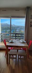 a dining room table with chairs and a large window at studio Loubat pyrénée, ménage inclus in Arette