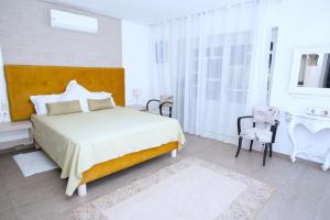 a white bedroom with a bed and a chair at Villa Zaara in Sehib Foukani +14 photos