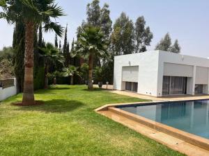 a house with a swimming pool in a yard with palm trees at Villa Zaara in Sehib Foukani