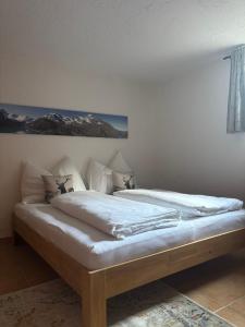 Una cama con sábanas blancas y almohadas en una habitación. en Haus Elisabeth, en Sankt Martin bei Lofer