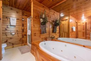 a bathroom with a tub and a toilet and wooden walls at Yearling in Banner Elk +12 photos