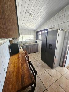 Una cocina con una mesa de madera y un refrigerador. en Casa Central Ubatuba, en Ubatuba 2 fotos más