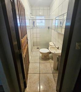 Un baño pequeño con inodoro y lavabo. en Casa Central Ubatuba, en Ubatuba