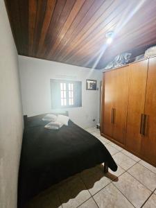 1 dormitorio con cama negra y techo de madera en Casa Central Ubatuba, en Ubatuba