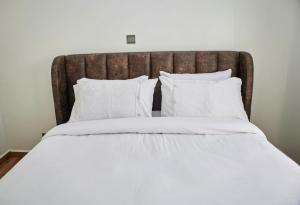 a large bed with white sheets and pillows at Juwell Haven in Nairobi +90 photos