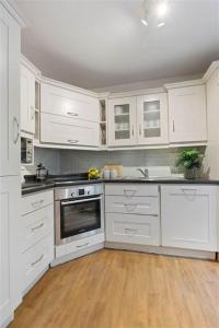 a white kitchen with white cabinets and a wooden floor at GuestReady - Coastal Charm near Sandymount Beach in Dublin