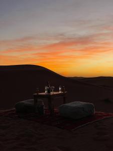 a table in the middle of the desert at sunset at Anssuf merzouga luxury camp in Merzouga