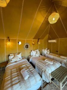 a room with three beds in a tent at Anssuf merzouga luxury camp in Merzouga