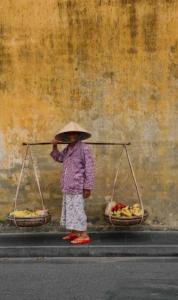 a woman wearing a hat with two baskets of fruit at Boutique Passion Hotel in Ho Chi Minh City