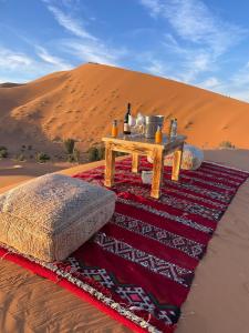 a table on a rug in the desert at Anssuf merzouga luxury camp in Merzouga +5 photos