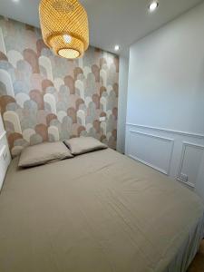a bedroom with a large bed and a chandelier at Appartement avec jardin - Front de mer St Laurent-du-Var in Saint-Laurent-du-Var