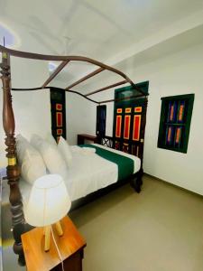 a bedroom with a bed and a table with a lamp at KAIMANA HOUSE - 3 Min walk to the beaches in Tangalle